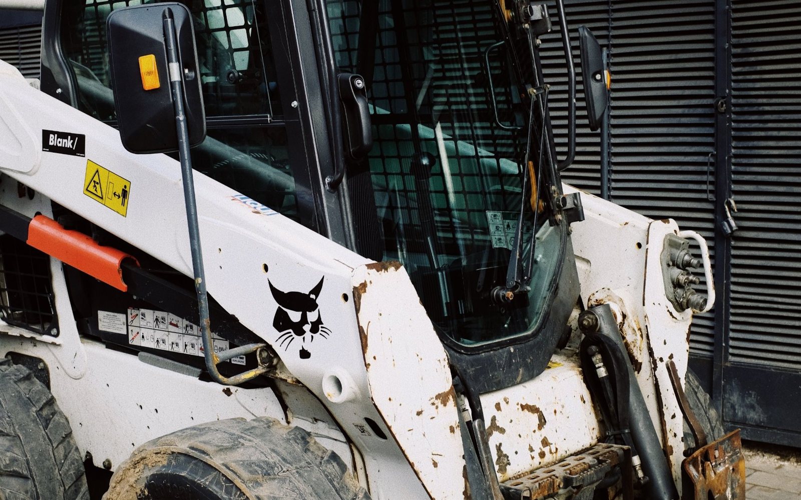 A skid steer loader parked outside a service building.